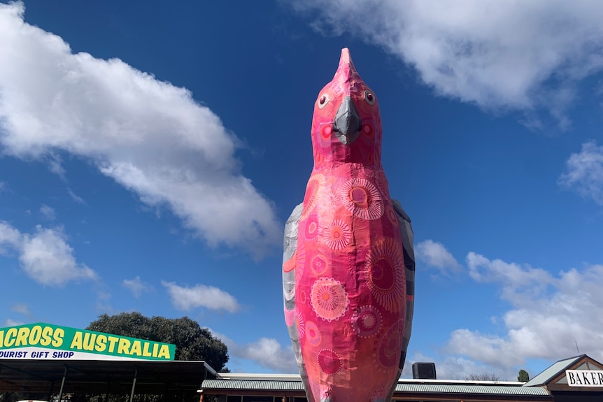 A massive pink gallah art piece with a blue sky backdrop.
