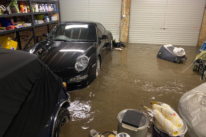 A car in a garage with water half-way up its body.