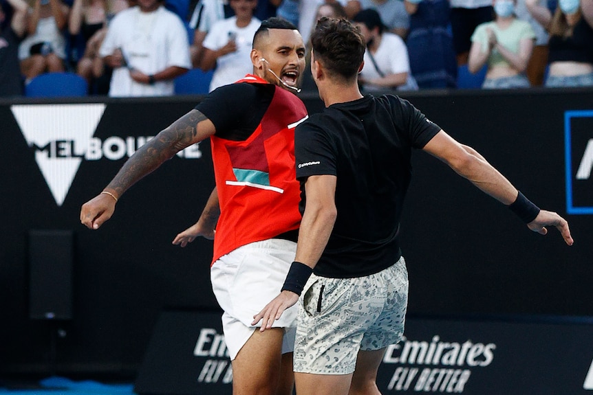 Two Australian male tennis players celebrate winning a doubles match.