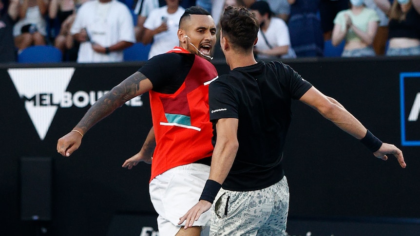 Two Australian male tennis players celebrate winning a doubles match.