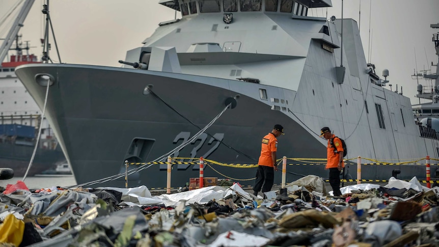Large ship in the background, with thousands of pieces of debris from doomed plane in the foreground