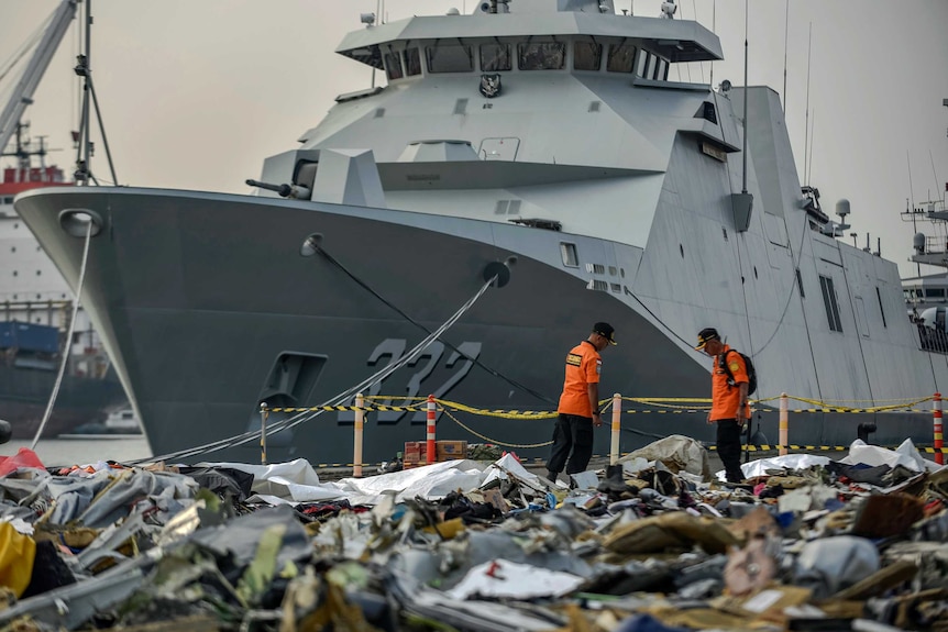 Large ship in the background, with thousands of pieces of debris from doomed plane in the foreground