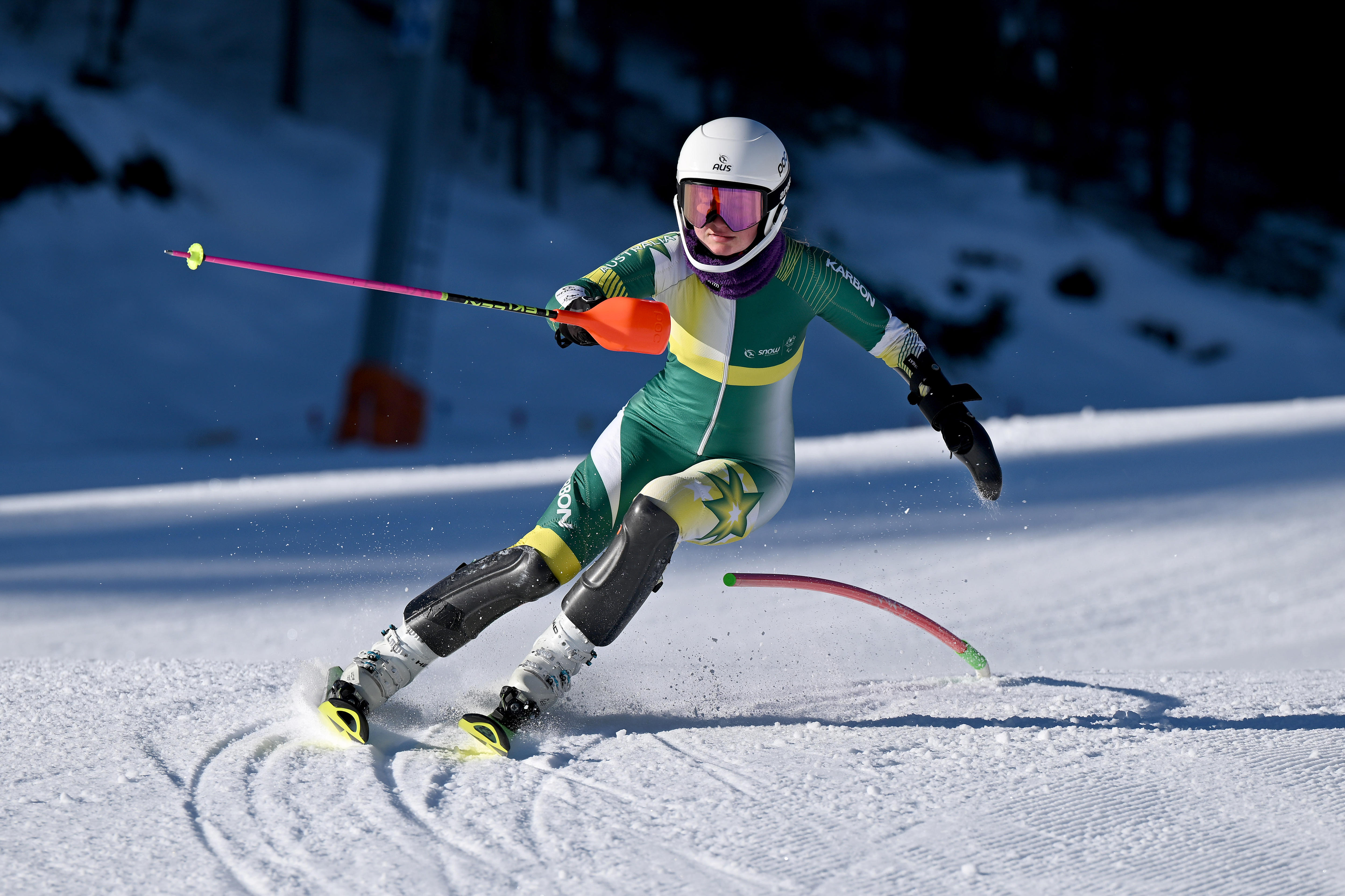 Um esquiador está se inclinando para uma curva, contornando um poste.