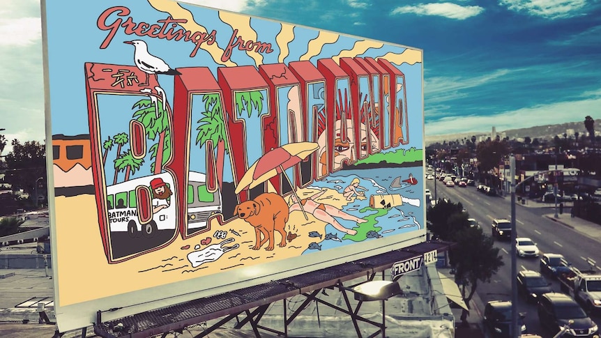 A billboard with an illustration reading "Greetings from Batmania" alongside a city street.