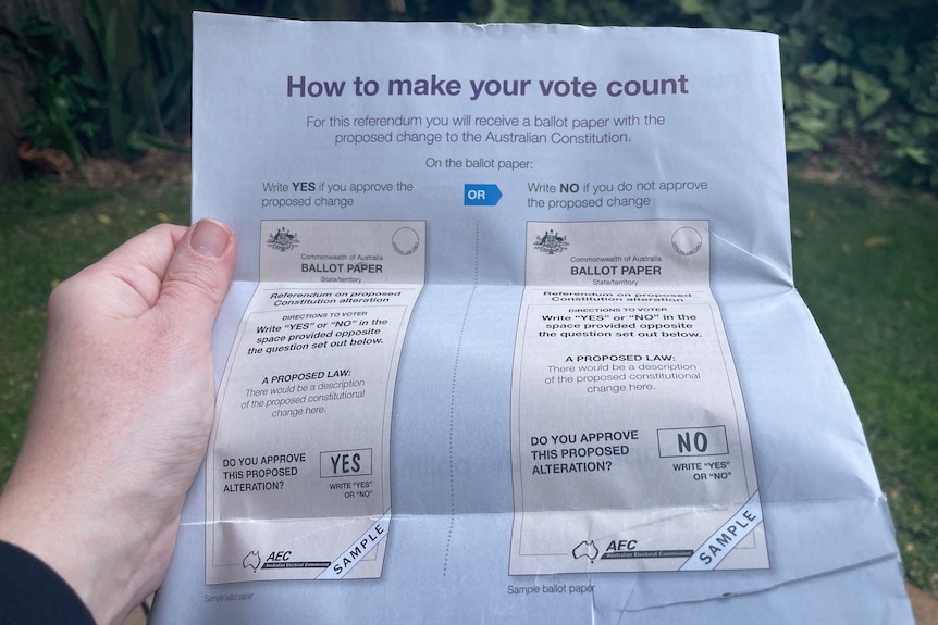 A person holding the Voice to Parliament referendum booklet with mock ballot papers 