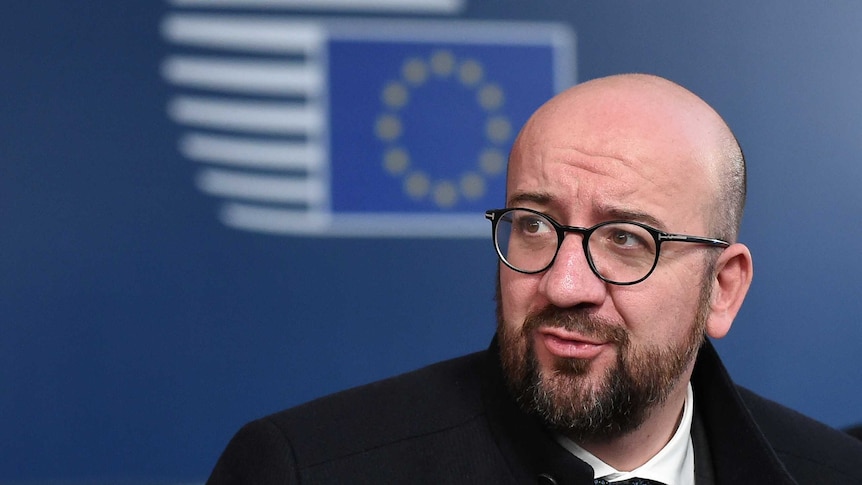 A man with glasses in front of an EU logo.