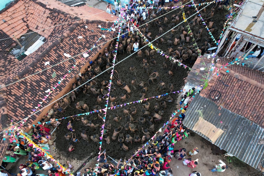 An aerial view shows men fling cow dung at each other.