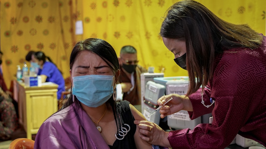 A health worker innoculates a woman with the COVID-19 jab at a vaccine center in Thimpu on july 26.