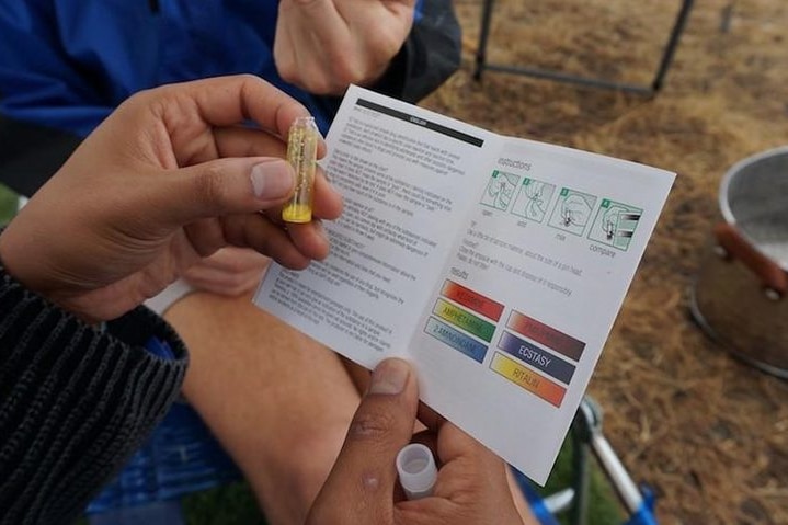 A hand holds a DIY drug testing kit, reading the available booklet.
