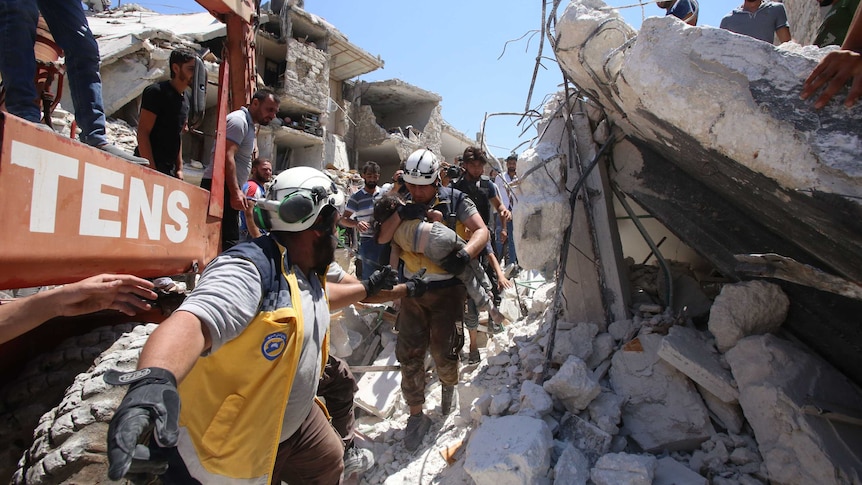 Members of the Syrian civil defence known as the White Helmets pull an injured child from the rubble in Idlib