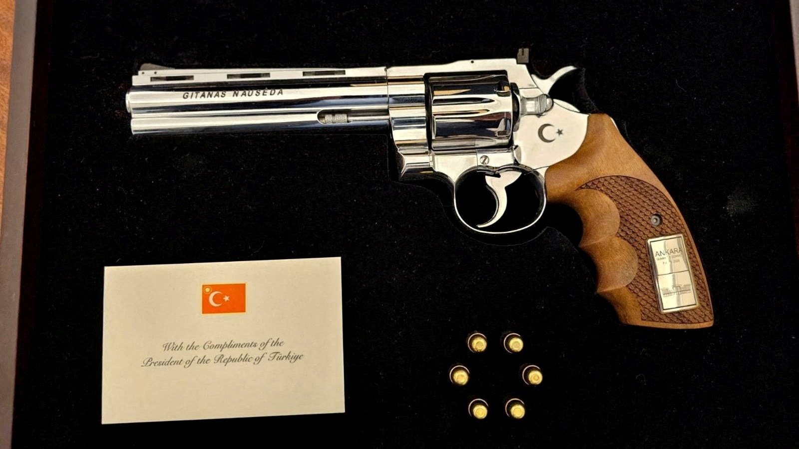 a shot gun with a wooden handle and a metal body in a black gift box and 6 bullets in a circle