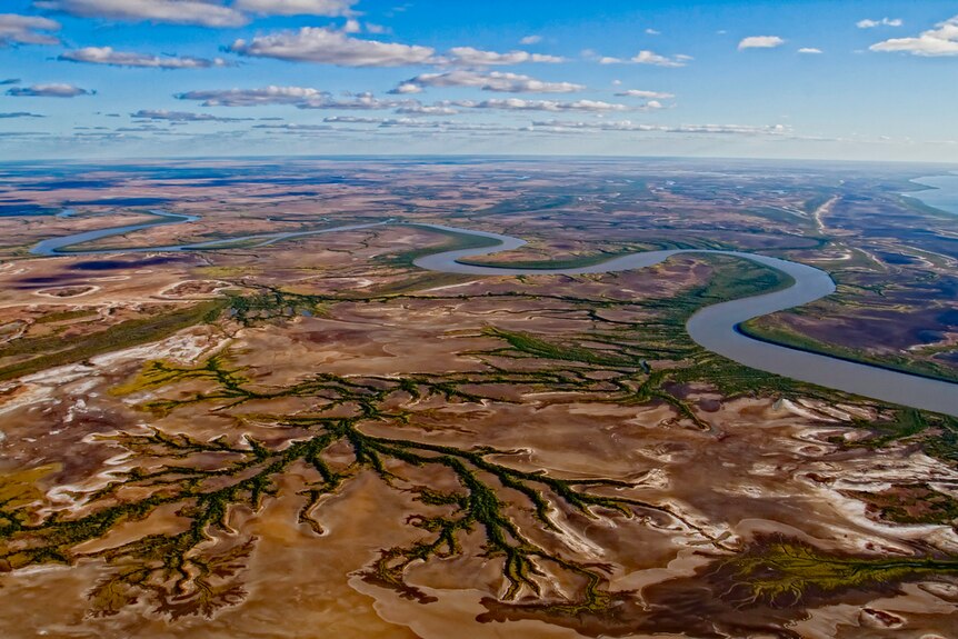 An aerial view of a vast, brown landscape with a river snaking through it.