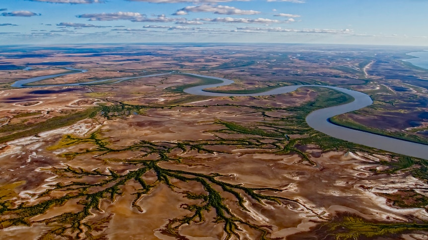 A river snakes through a combination of green and brown land.