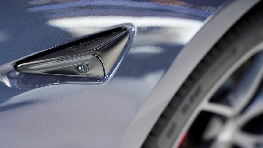 In a close up image of a Tesla car headlight, a camera can be seen within the headlight 