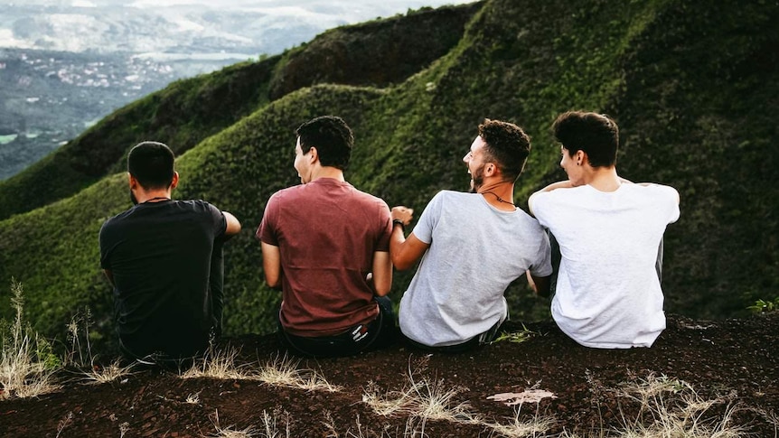 Four teenage boys sit together in a row.