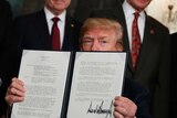 Donald Trump displays signs a memorandum imposing tariffs on China