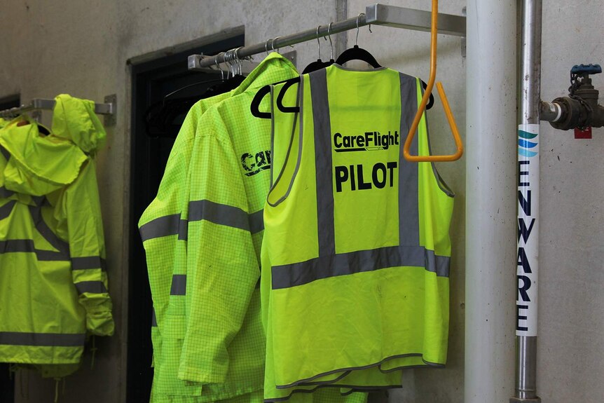 A high-vis Careflight Pilot vest hangs on a rack with others.