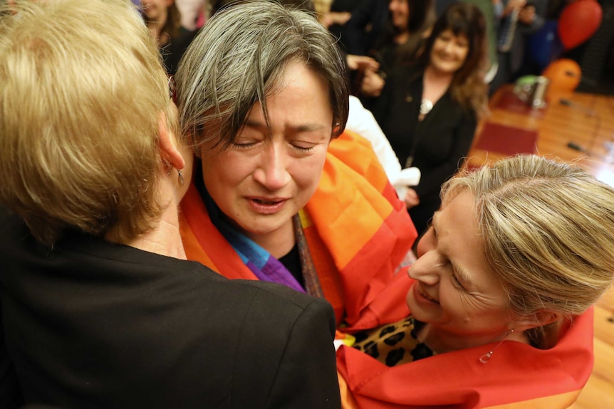 Penny Wong appears overcome by emotion as she wears a rainbow flag