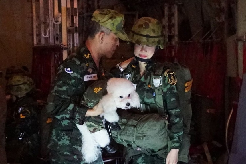 Dressed in military uniforms, King Maha Vajiralongkorn is holding a poodle next to royal consort Sineenat Wongvajirapakdi.