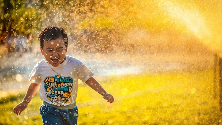 Kid running through a sprinkler in the yard