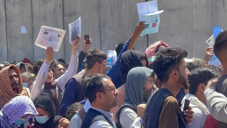 Afghan people desperate to leave the country wave their documents outside Kabul airport