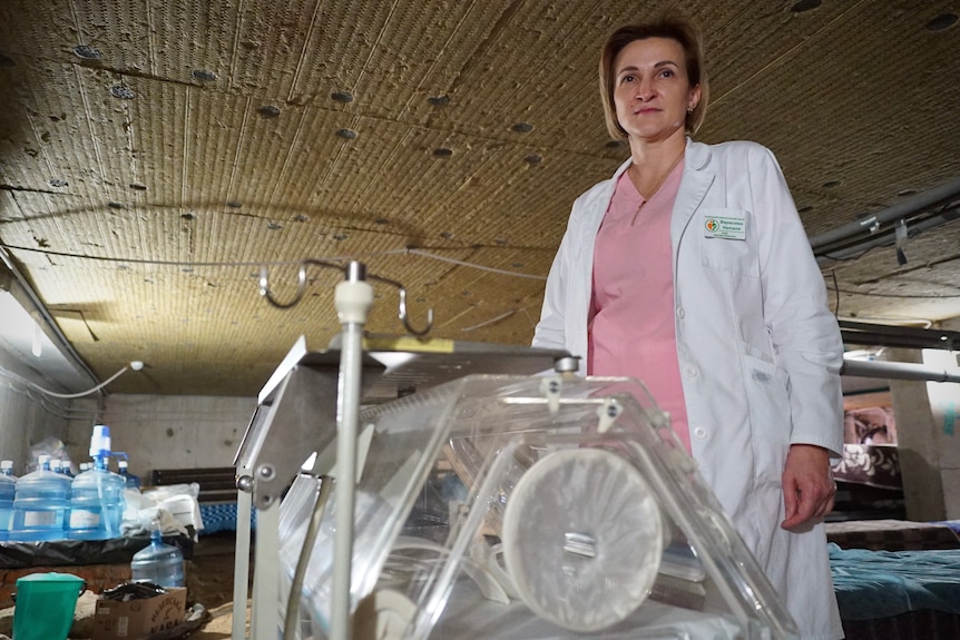 A female doctor stand by an neo-natal incubator machine in a hospital basement.