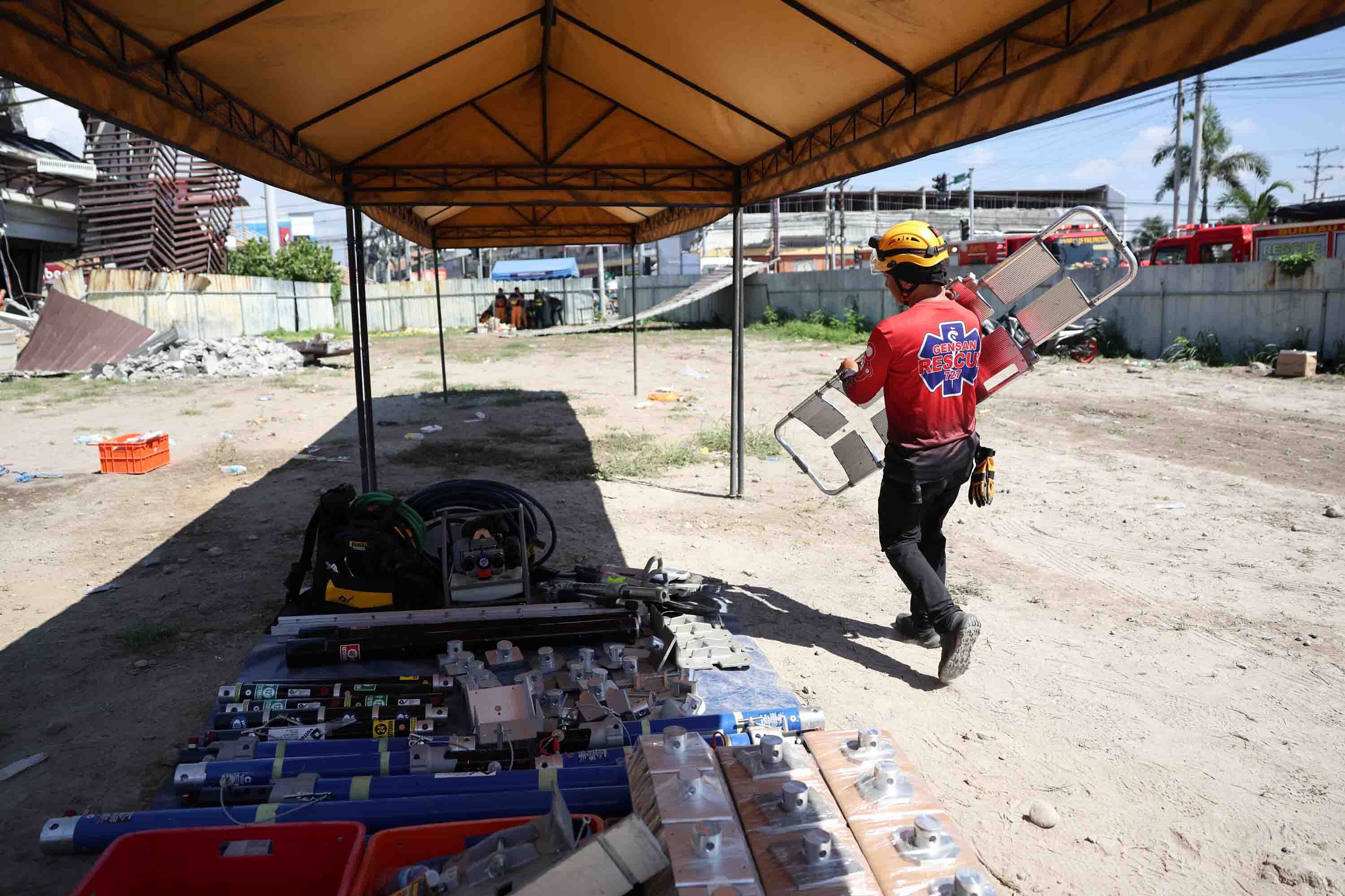 A man carries a stretcher beneath a marquee.
