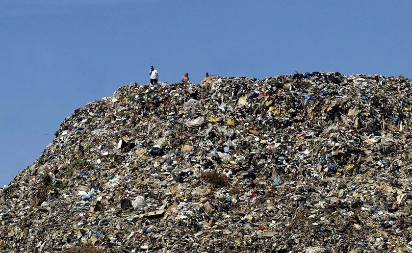 Lebanese men stand on top of a mountain of garbage
