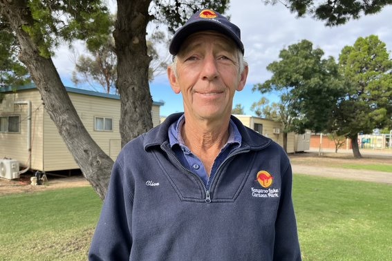 A man in front of a tree in a caravan park.