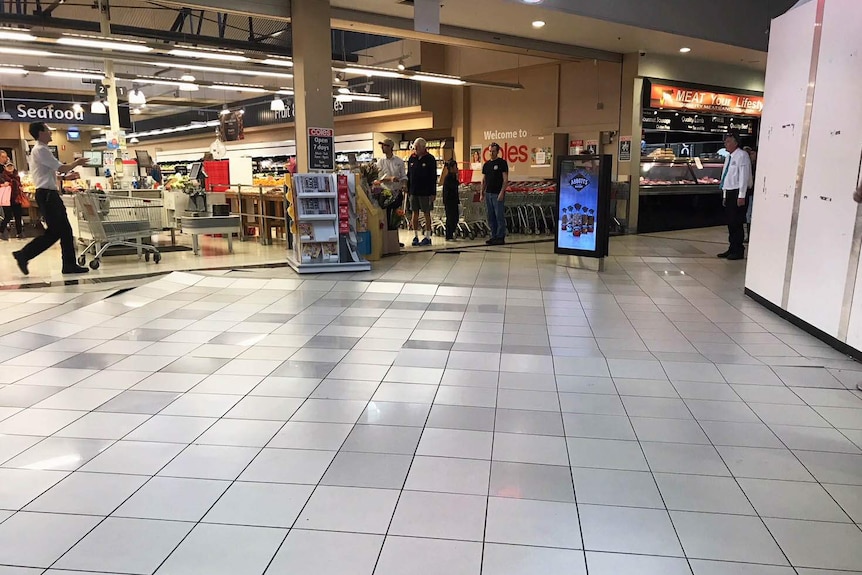 Tiles lifting in lines on a floor outside a Coles supermarket