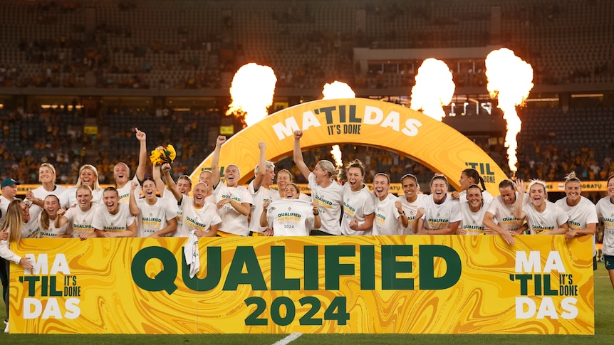 Matildas celebrate qualifying for the Olympics behind a big sign reading "Qualified 2024".