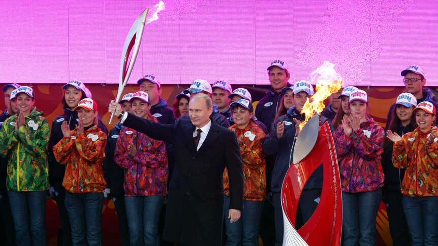 Vladimir Putin holds a Olympic torch to mark the start of the Sochi 2014 Winter Olympics torch relay.