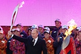 Vladimir Putin holds a Olympic torch to mark the start of the Sochi 2014 Winter Olympics torch relay.