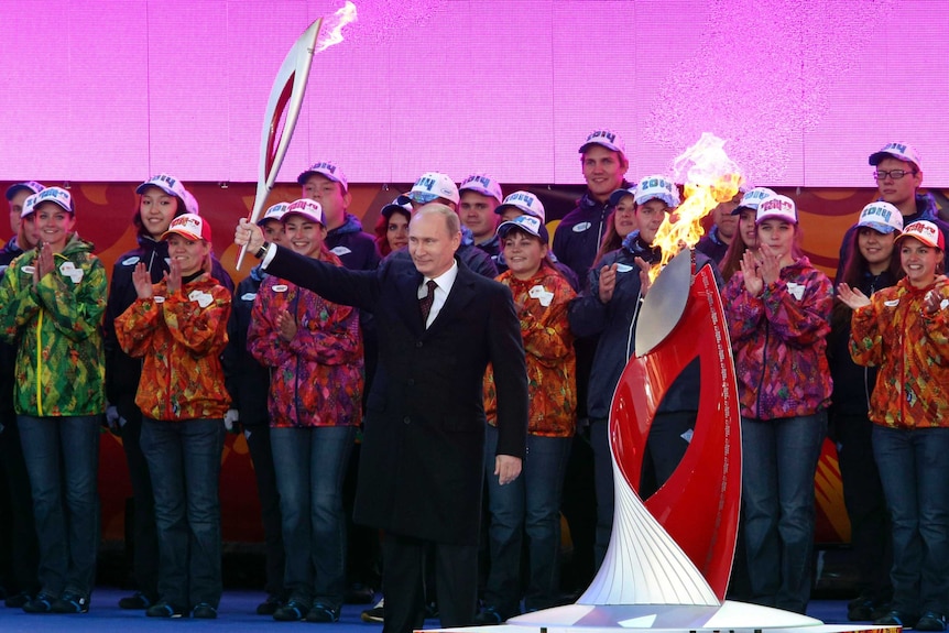 Vladimir Putin holds a Olympic torch to mark the start of the Sochi 2014 Winter Olympics torch relay.