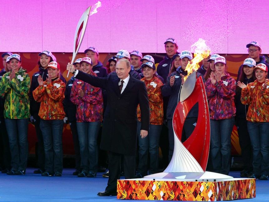 Vladimir Putin holds a Olympic torch to mark the start of the Sochi 2014 Winter Olympics torch relay.