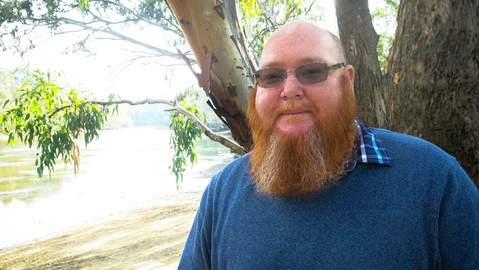 Rene Woods stands on the river bank above the Murray river.