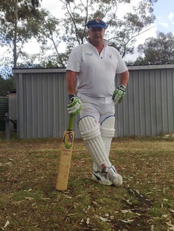 Brett Kelly in cricket pads and gloves with a cricket bat