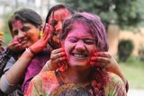 Indian girls play with colored powder during Holi festival