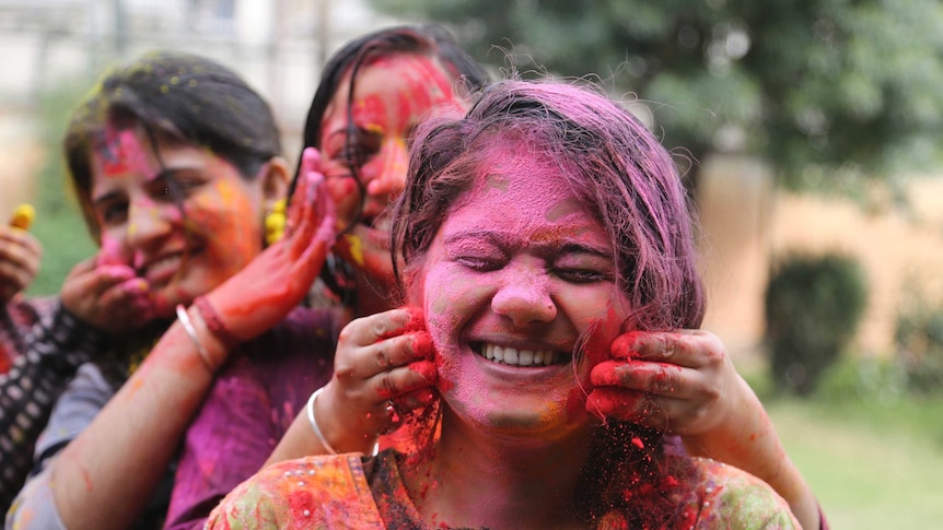 Indian girls play with colored powder during Holi festival