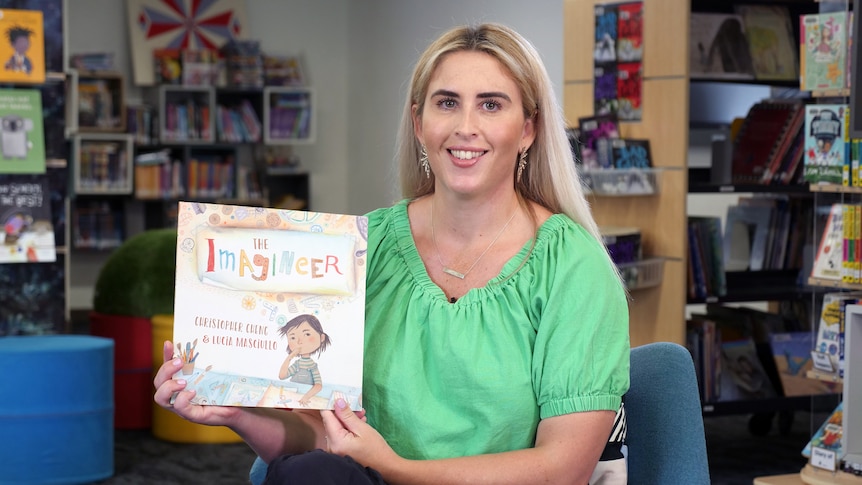 Mrs Ryan holds up story book with title The Imagineer