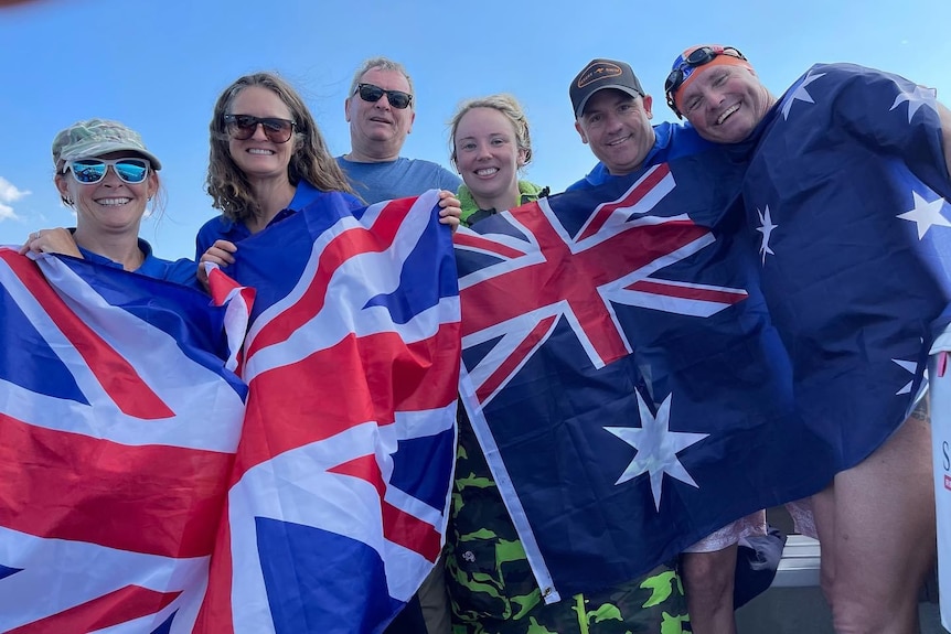 A group of people hold up British and Australian flags.
