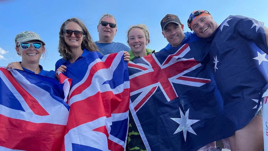 six people hold up an australian flag