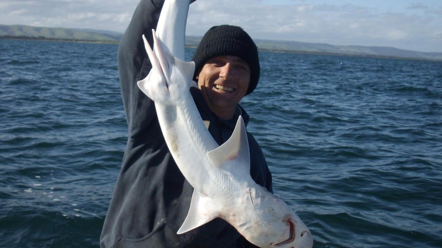 Trevor McKie holding a fish sitting on a boat