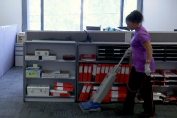 Cleaner Mary Rizk using a vacuum cleaner in an office.