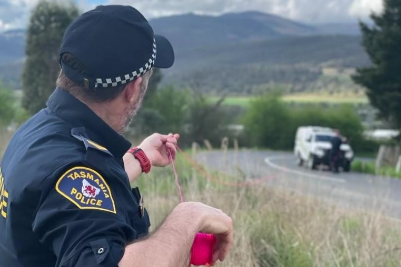 Tasmania Police officer taking measurements at the scene where a police car was shot at.