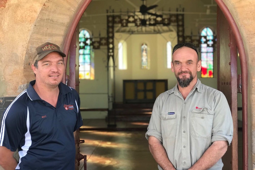 mid shot of two workers - the Anglican Church's Matt Warth, and builder David Baessler, at the open doors to the church