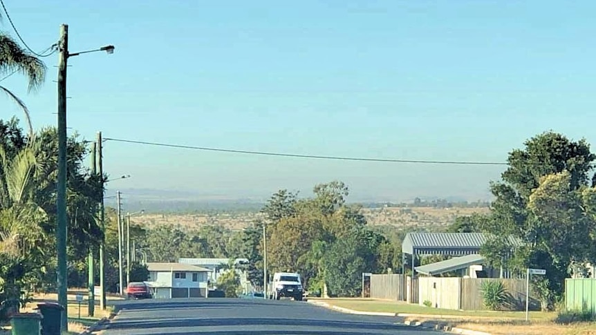 view of a suburban street looking out to dust on the horizon.