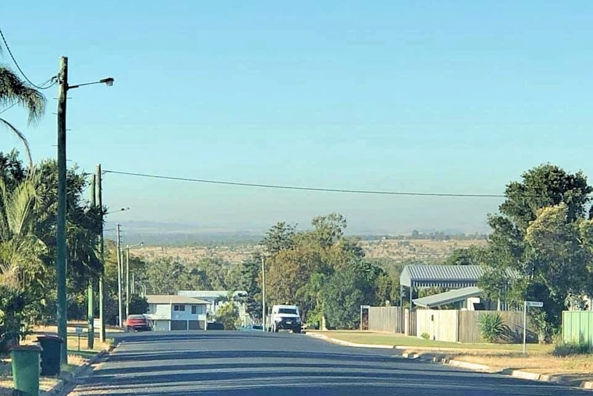 view of a suburban street looking out to dust on the horizon.