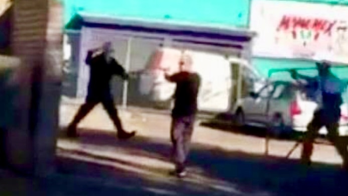 Grainy mobile phone footage of three men on a street.