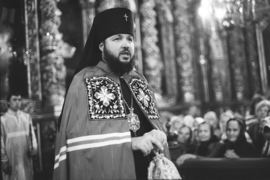 A black and white photo of Patriarch Kirill dressed in religious robes delivering a speech in church.
